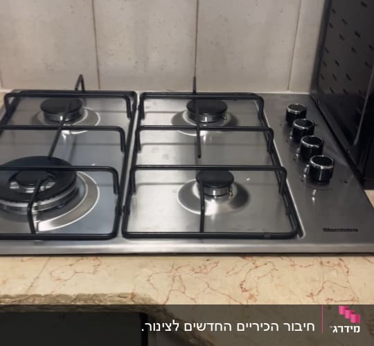 כיריים גז עם ארבעה מבערים על משטח שיש